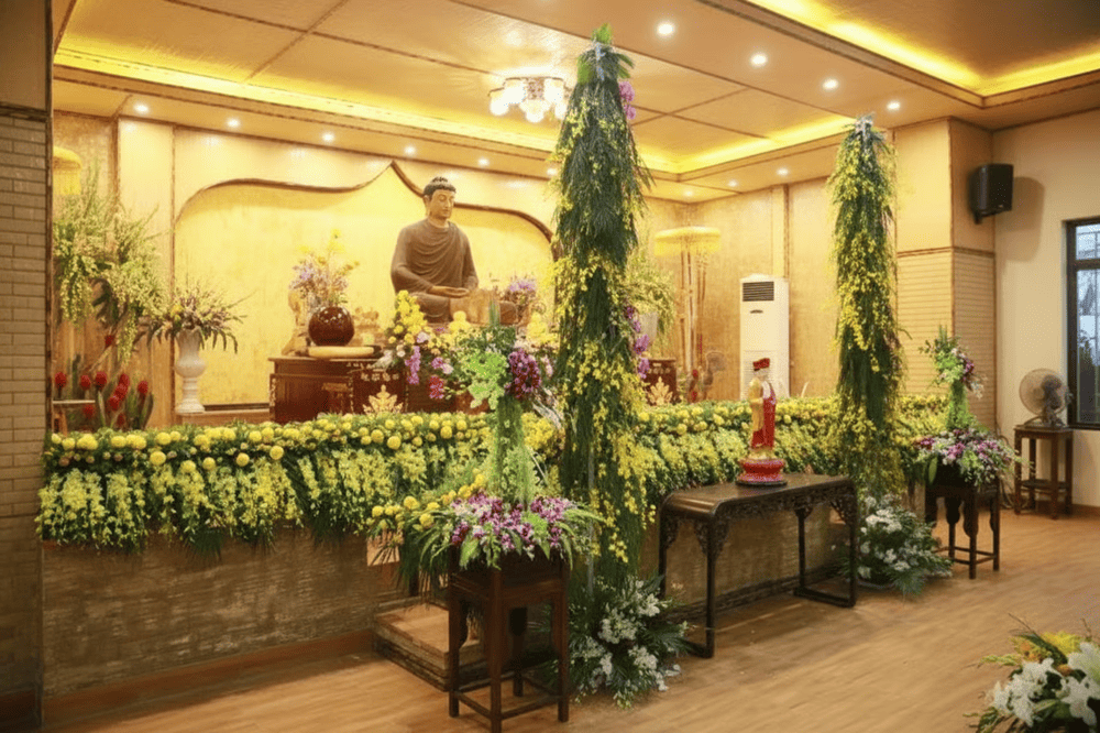 Tượng Phật trang nghiêm trong điện thờ chính, tôn lên bởi ánh sáng vàng ấm và rừng hoa tươi thắm đầy sắc màu tạo không gian an lạc.